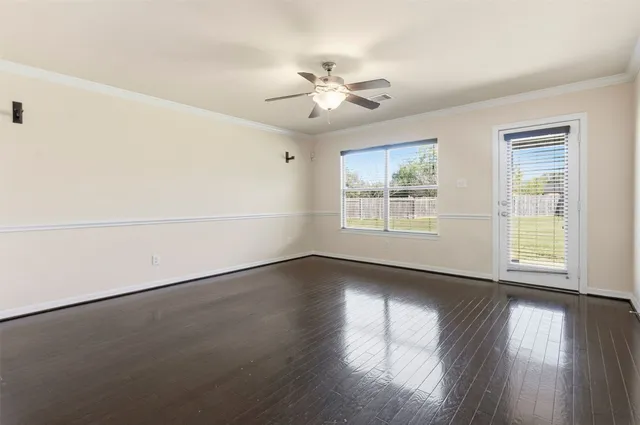 an empty room with wooden floor chandelier fan and windows
