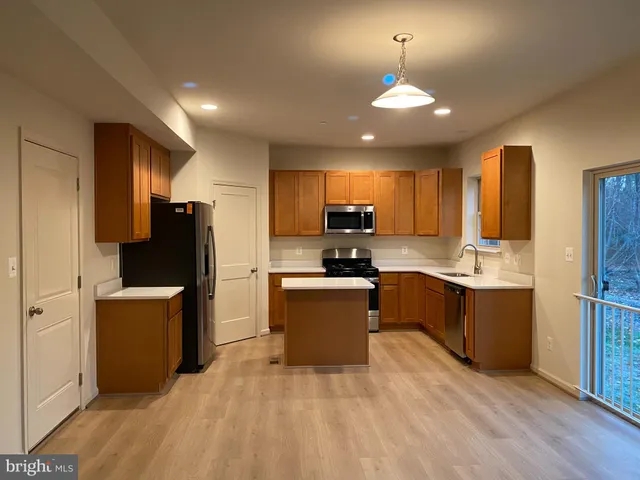 a kitchen with refrigerator a stove a sink cabinets and wooden floor