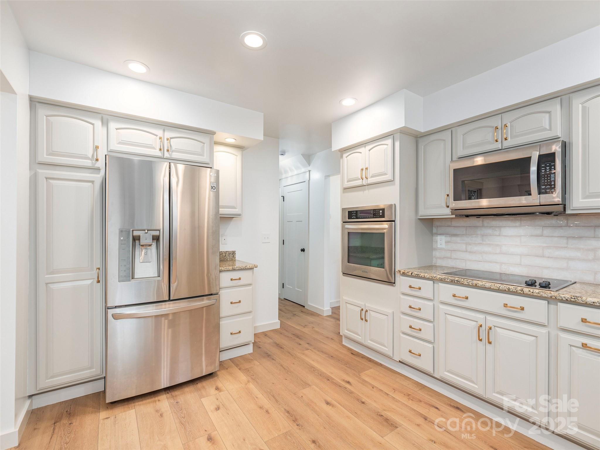 93 Cresthaven Drive Clyde, NC 28721 - Photo 11 of 27 a kitchen with stainless steel appliances white cabinets and wooden floor
