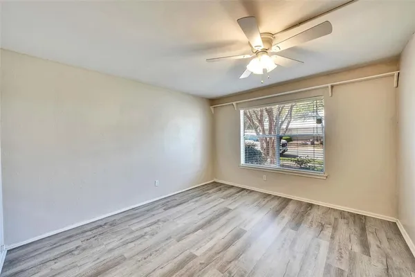 an empty room with wooden floor chandelier fan and windows