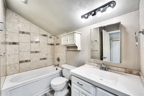 a bathroom with a sink a toilet a mirror a bathtub and shower