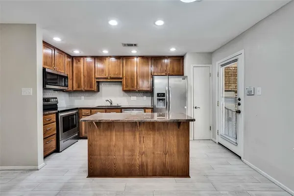 a kitchen with kitchen island stainless steel appliances a sink stove and refrigerator