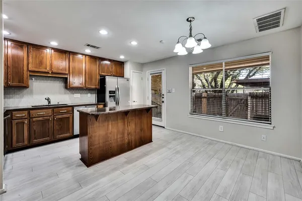 a kitchen with stainless steel appliances granite countertop a stove top oven a sink dishwasher a dining table and chairs with wooden floor