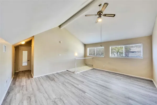 a view of empty room with wooden floor and fan