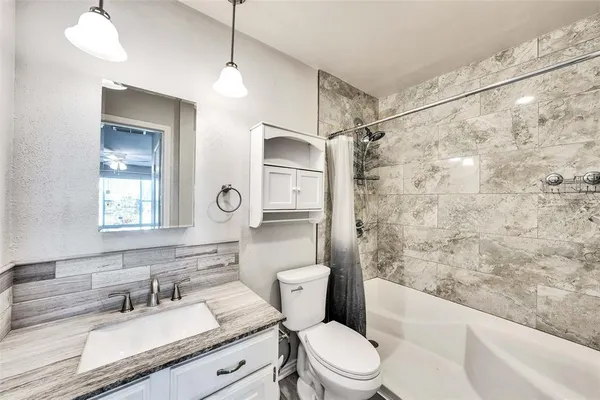 a bathroom with a sink a toilet a mirror and shower