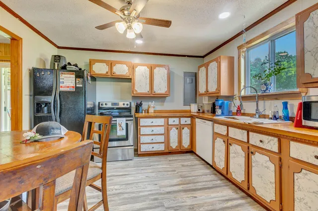 a kitchen with stainless steel appliances granite countertop a refrigerator a sink dishwasher a stove and white countertops with wooden floor