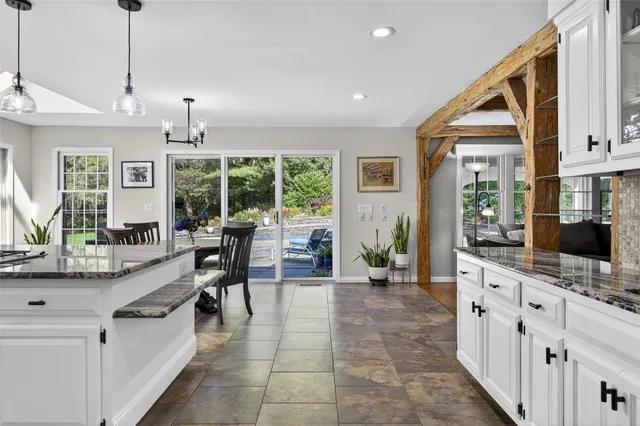 a large white kitchen with granite countertop a stove a sink a dining table and chairs