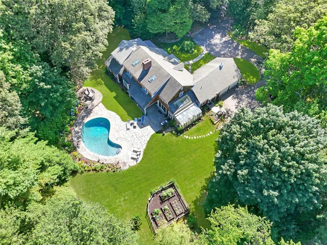 an aerial view of a house with swimming pool and large trees