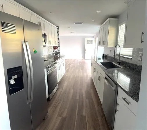 a kitchen with stainless steel appliances granite countertop a refrigerator a stove a sink and a microwave