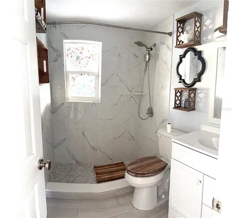 a bathroom with a granite countertop sink a toilet and shower