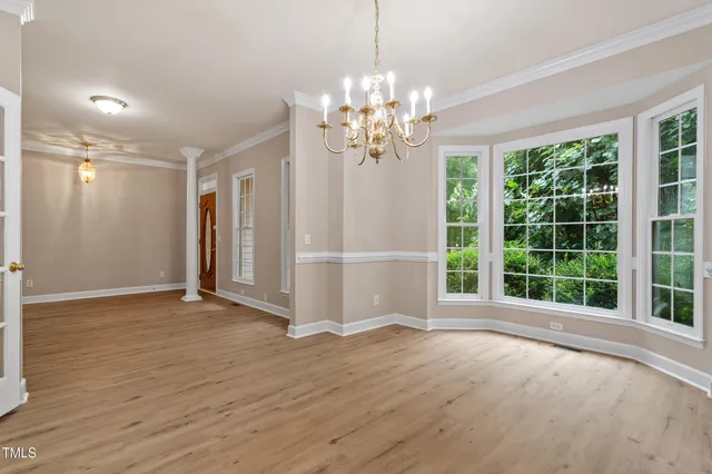 a view of an empty room with a window and wooden floor