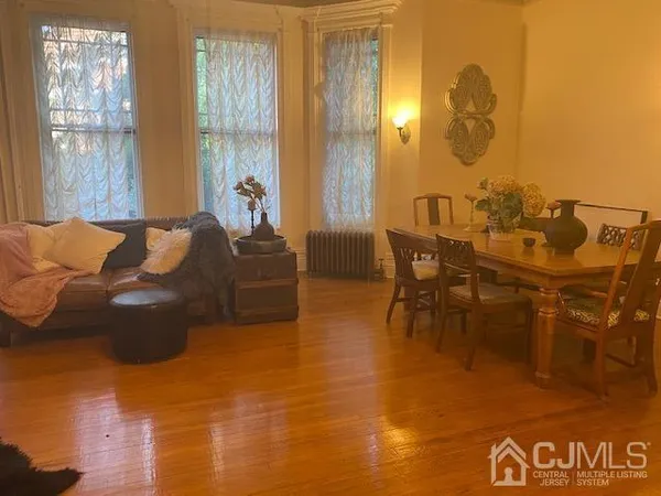 a living room with couches painting on the wall and a large window