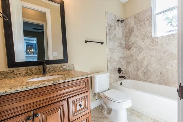 a bathroom with a granite countertop toilet sink and mirror