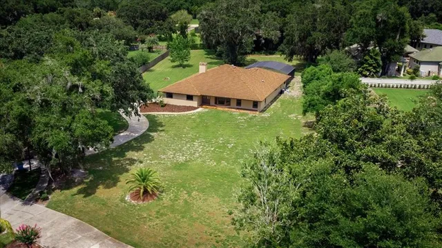 an aerial view of a house with yard and trees all around