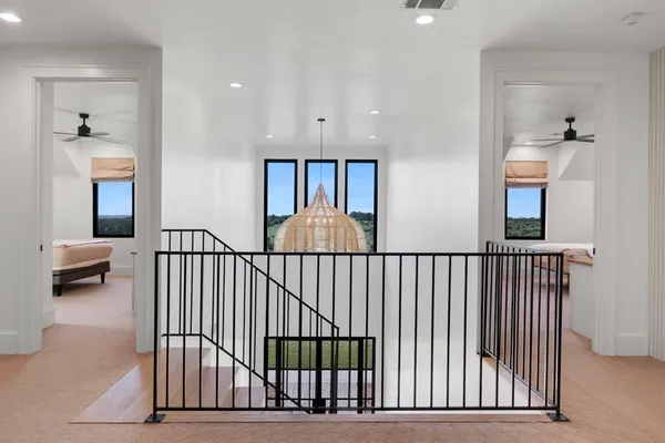 a view of a big room with windows and chandelier fan