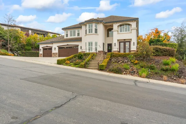 a front view of a house with a garden and trees