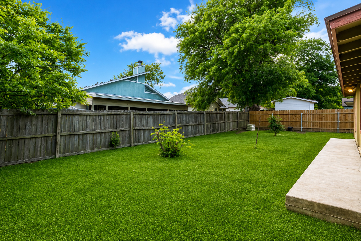 5611 Meadow Crest Austin, TX 78744 - Photo 6 of 29 A fenced backyard offers a verdant lawn and a spacious concrete patio for outdoor enjoyment.
