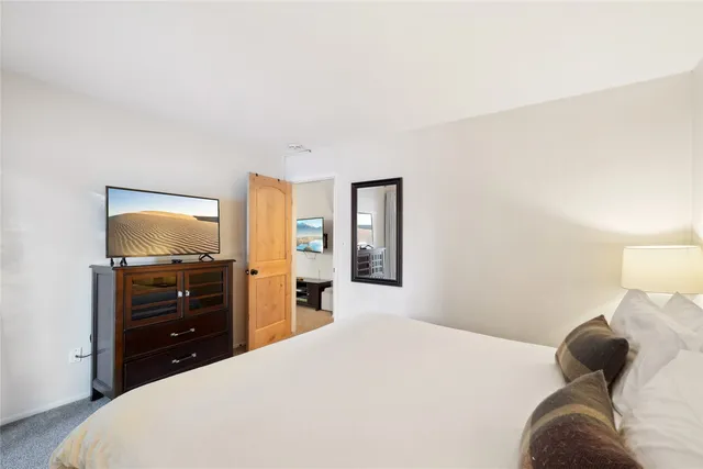 a bedroom with a bed and a flat tv screen on dresser