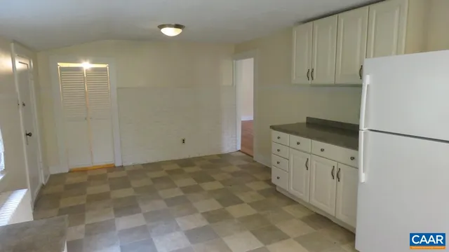 a kitchen with granite countertop white cabinets and refrigerator