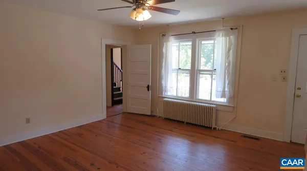 a view of an empty room with wooden floor and a window