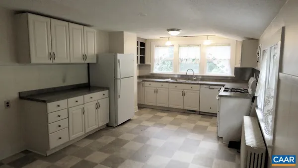 a kitchen with white cabinets and refrigerator