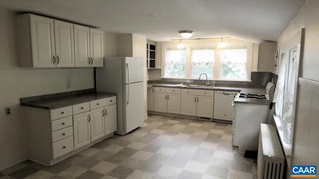 a kitchen with white cabinets and refrigerator