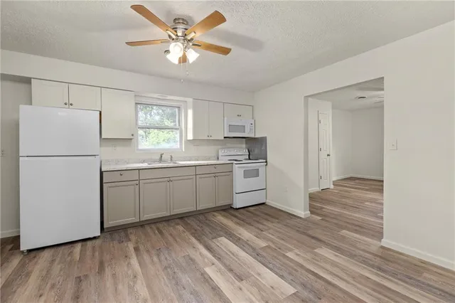 a kitchen with a refrigerator a sink and dishwasher with wooden floors