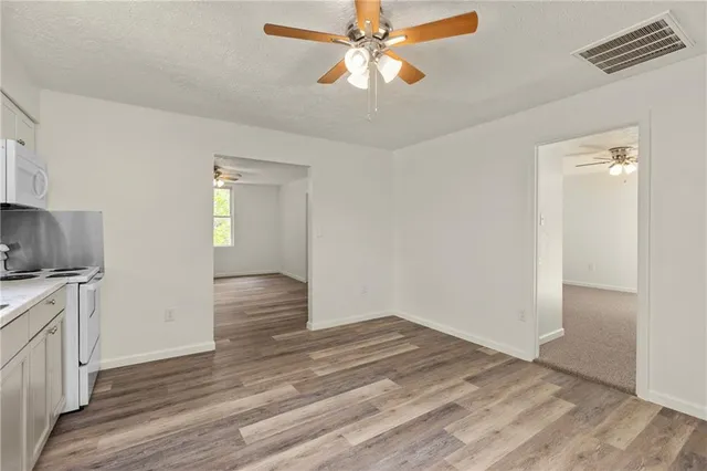 a view of empty room with wooden floor and fan