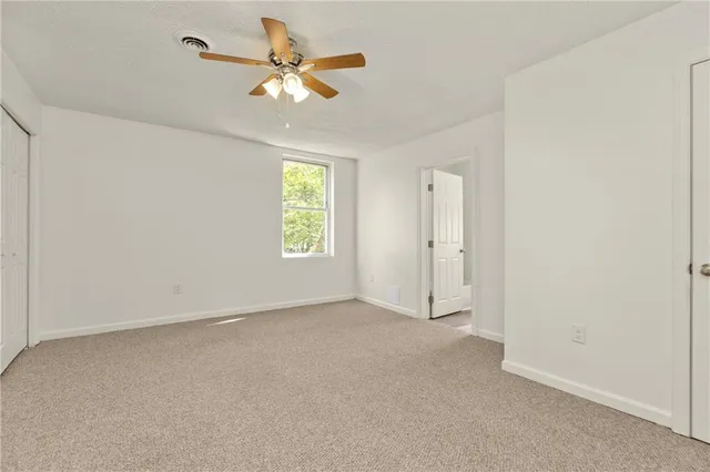 an empty room with a window and a fan