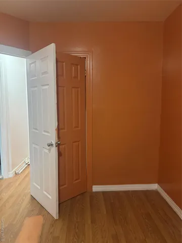 a view of an empty room with wooden floor and closet