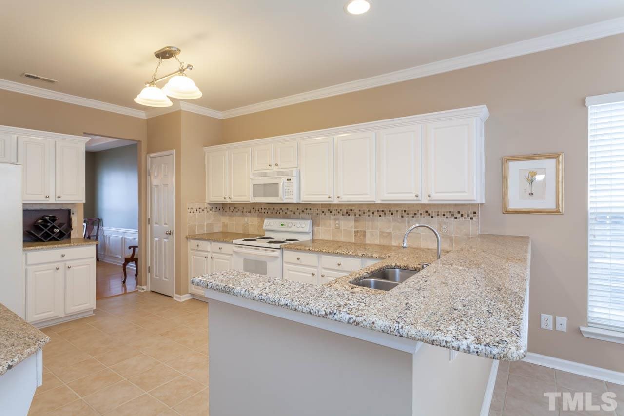 7472 Silver View Lane Raleigh, NC 27613 - Photo 5 of 25 a kitchen with a sink dishwasher a stove and white cabinets with wooden floor