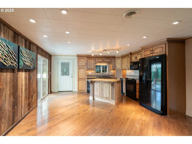 a open kitchen with stainless steel appliances kitchen island granite countertop a refrigerator a sink and a stove