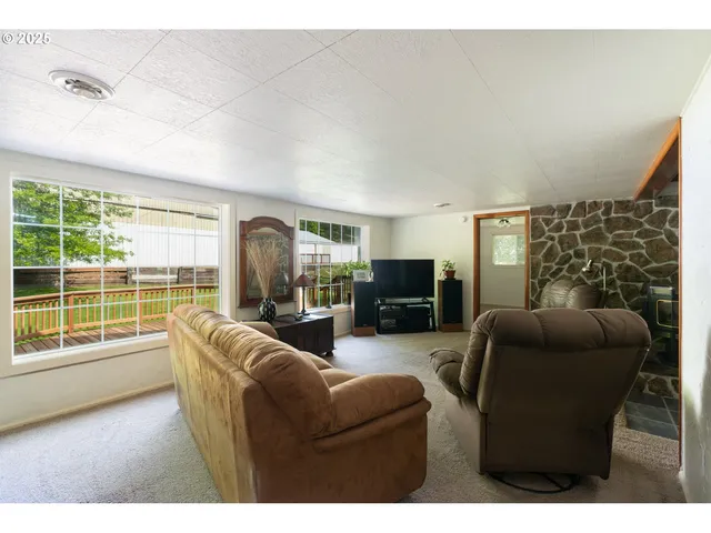 a living room with furniture a flat screen tv and a floor to ceiling window