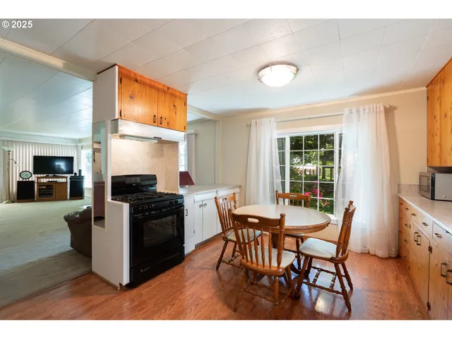 a kitchen with stainless steel appliances kitchen island granite countertop a table chairs and a refrigerator
