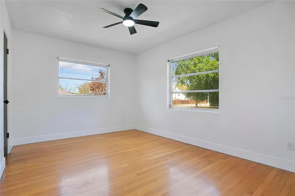 a view of empty room with wooden floor and fan