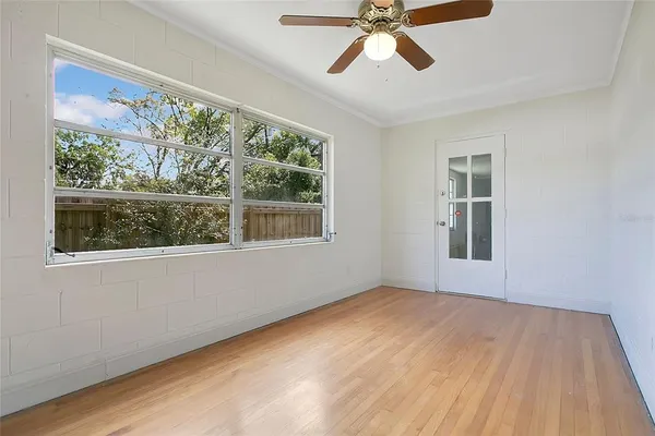 a view of an empty room with wooden floor and a window
