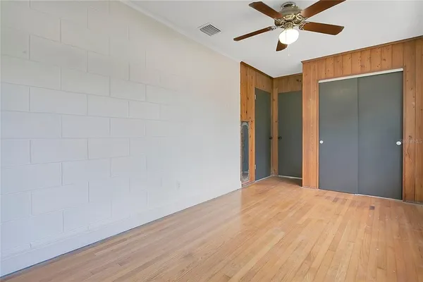 a view of a big room with wooden floor and a chandelier fan in a room