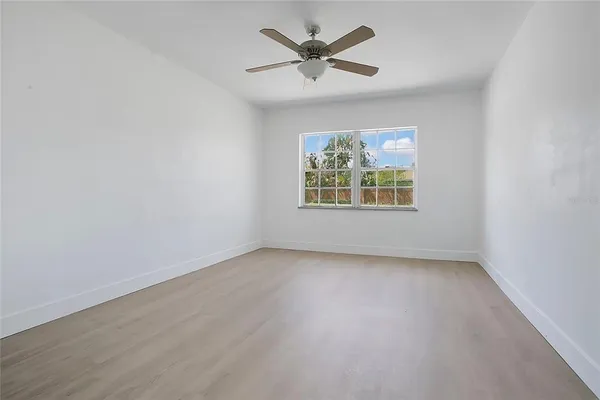 an empty room with windows and a ceiling fan