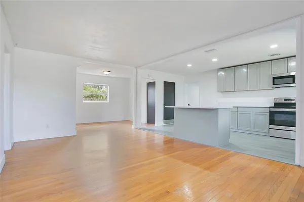 a view of a kitchen with a sink stove cabinets and empty room