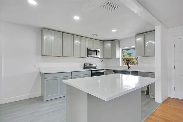 a kitchen with a sink a counter top space stainless steel appliances and cabinets
