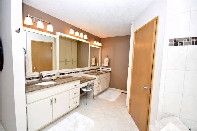 a spacious bathroom with a double vanity sink a mirror and a bathtub