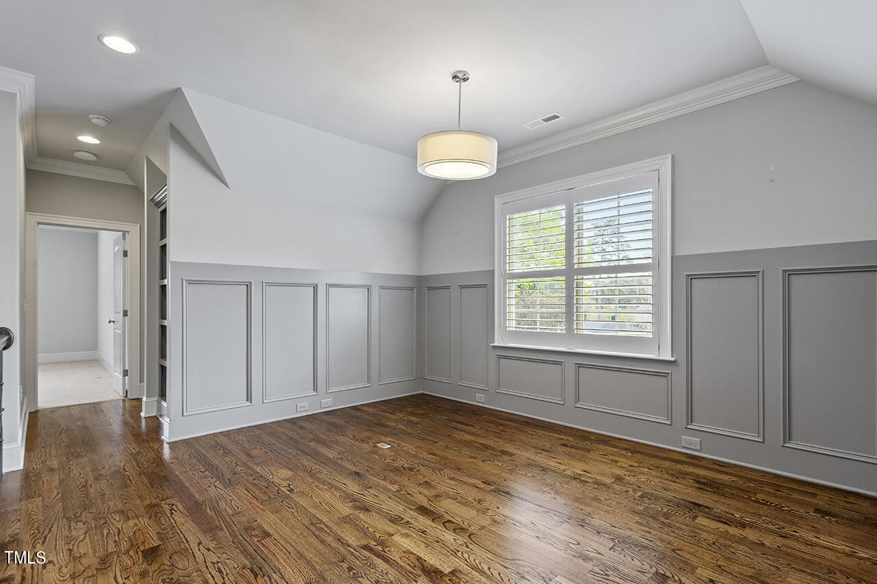 3601 Laurel Hills Road Raleigh, NC 27612 - Photo 42 of 77 an empty room with wooden floor chandelier and windows