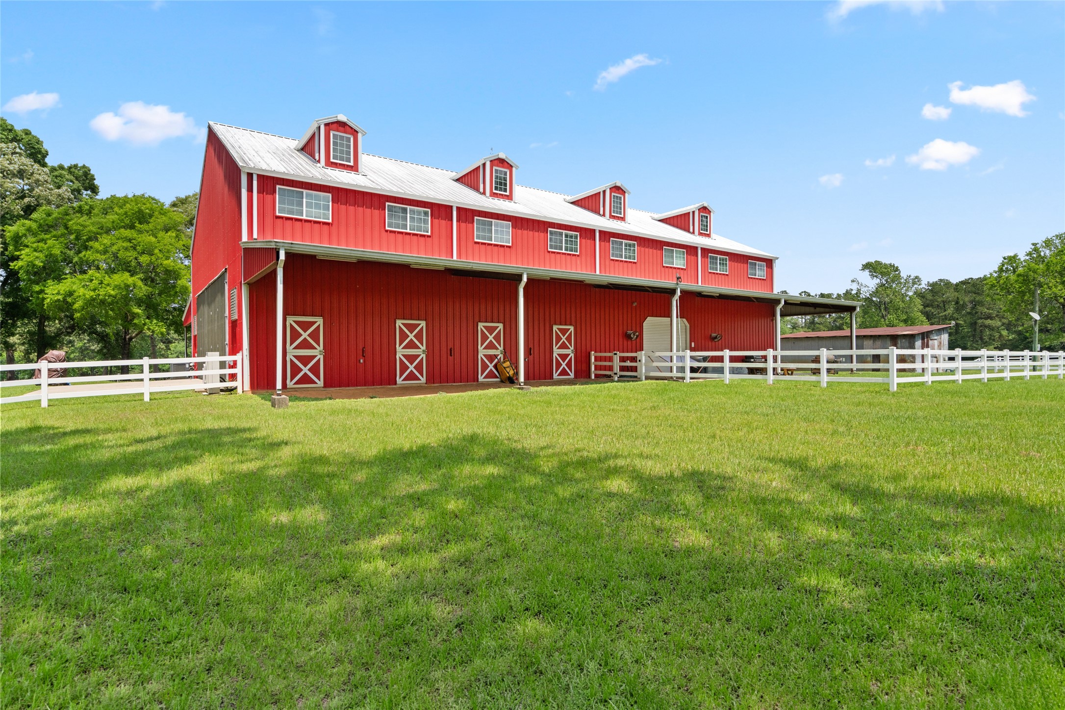 15126 Walden Road Montgomery, TX 77356 - Photo 16 of 50 Impressive red barndominium with striking exterior, white picket fence, and an open field arranged purposefully on the property.