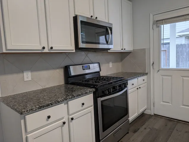 a kitchen with granite countertop a stove top oven a sink dishwasher and wooden cabinets