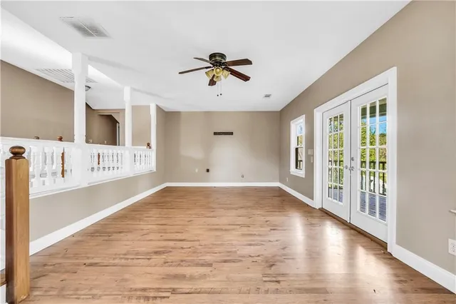 an empty room with wooden floor fan and windows