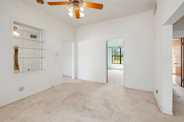 an empty room with windows and chandelier fan