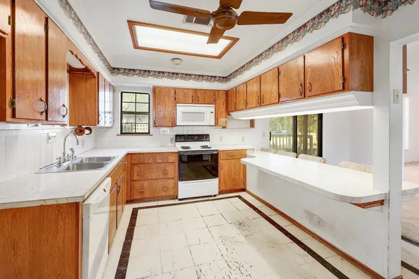 a large white kitchen with stainless steel appliances granite countertop a sink and a stove