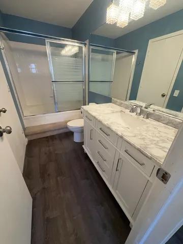 a bathroom with a granite countertop sink a toilet and shower