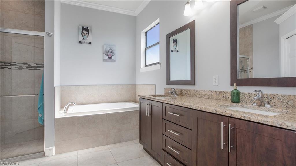 6341 Green Boulevard Naples, FL 34116 - Photo 15 of 48 a bathroom with a granite countertop bathtub shower sink vanity and mirror