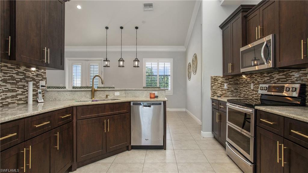 6341 Green Boulevard Naples, FL 34116 - Photo 29 of 48 Kitchen with appliances with stainless steel finishes, crown molding, a sink, tasteful backsplash, and plenty of natural light